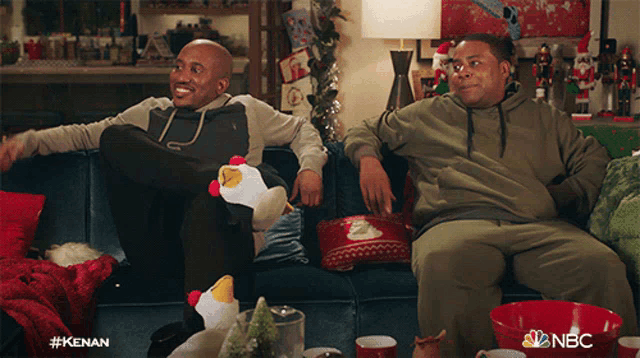 two men are sitting on a couch with the nbc logo on the bottom right