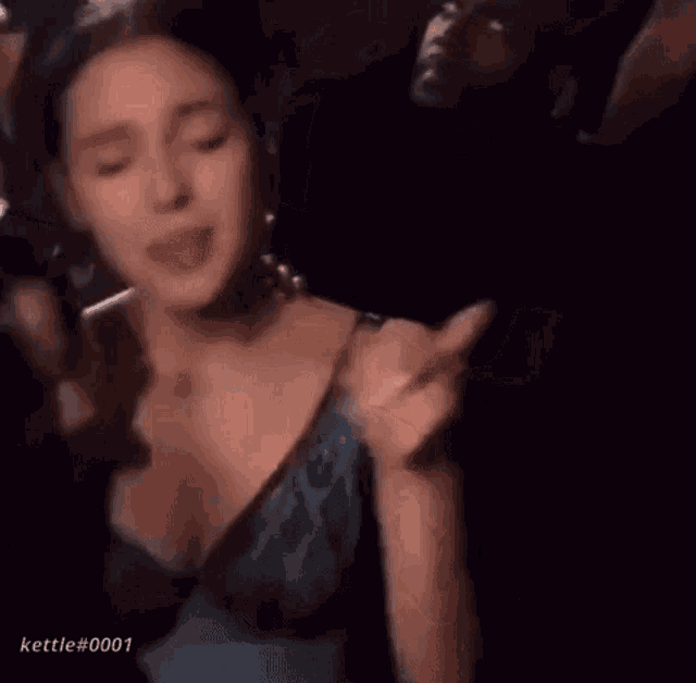 a woman in a blue dress is singing into a microphone in a crowd .