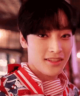a close up of a young boy wearing a red and white striped shirt and a red jacket .