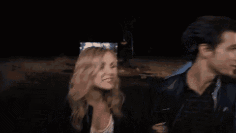 a group of people are standing next to each other in a dark room and a man is singing into a microphone .