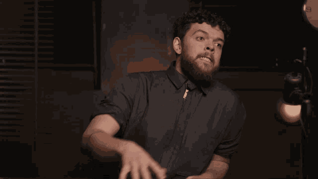 a man with a beard wearing a black shirt with a zipper on the front