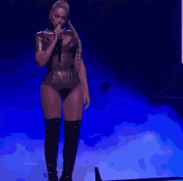 a woman is standing on a stage holding a microphone and wearing thigh high boots .