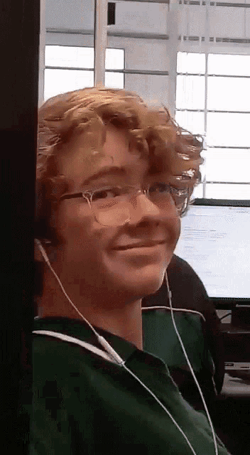 a young man wearing headphones and a green shirt smiles for the camera