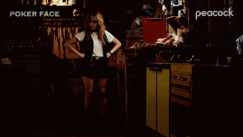 a woman stands in a dark room with peacock written on the corner