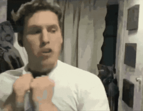 a man in a white shirt is tying a bow tie