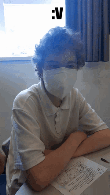 a boy wearing a face mask is sitting at a desk