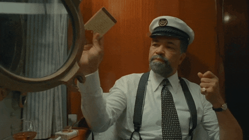 a man in a captain 's hat is holding a piece of paper
