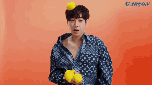 a man wearing a louis vuitton jacket holds lemons