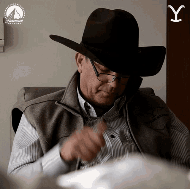 a man wearing a cowboy hat and glasses is sitting in a chair with a paramount network logo behind him
