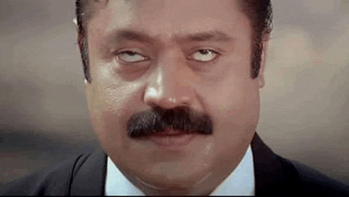the man is wearing a suit and tie and has a mustache .