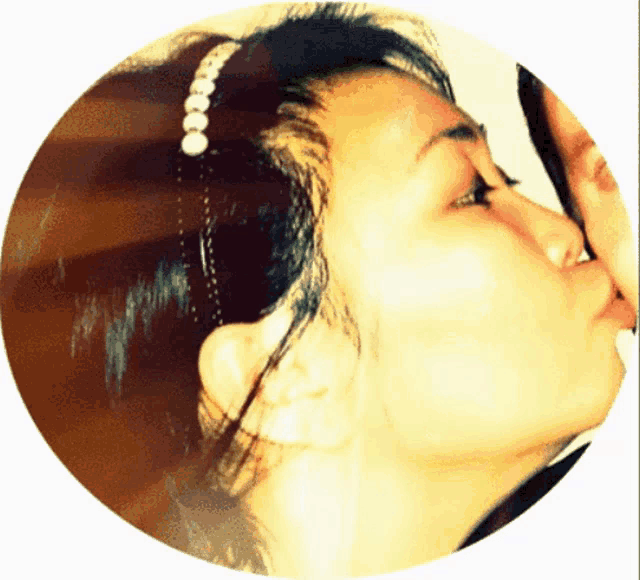 a woman wearing a headband with pearls on it kissing another woman
