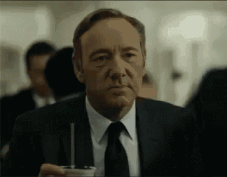a man in a suit and tie is holding a cup with a straw