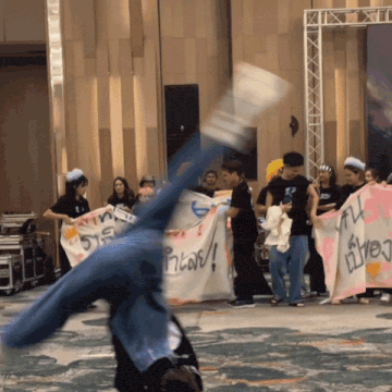 a person is doing a handstand in front of a group of people holding signs one of which says ' a '