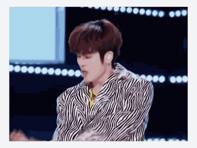 a man in a zebra print jacket is dancing on a stage .