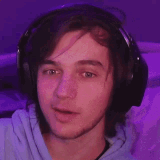 a young man wearing headphones and a hoodie is smiling .
