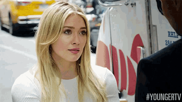 a woman in a white sweater is talking to a man in front of a white truck that says rhh on it