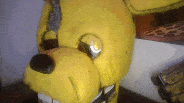 a close up of a yellow stuffed animal with a pizza on the background
