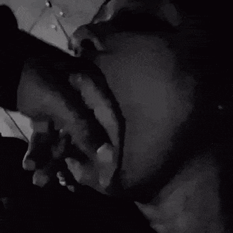it is a black and white photo of a woman smoking a cigarette and smiling .