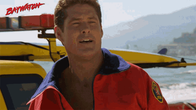 a man wearing a red jacket with the word baywatch on it