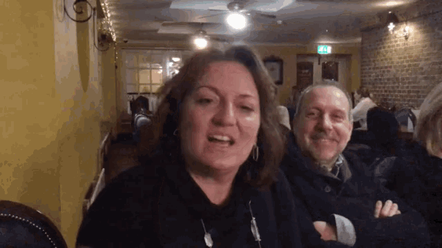 a man and a woman are sitting in a restaurant with a green exit sign on the wall