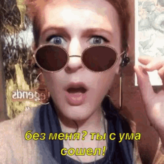 a woman wearing sunglasses has a surprised look on her face and says " без меня " in yellow letters