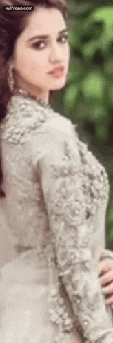 a woman in a white dress is standing in front of a tree .