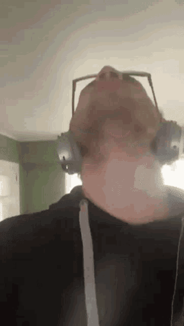 a man wearing headphones and glasses is looking up at the sky .