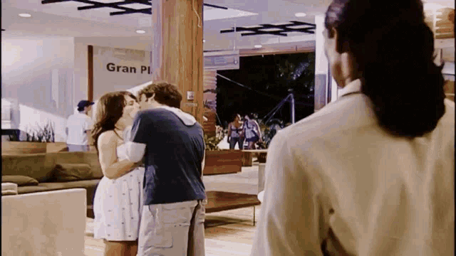 a man and woman are kissing in front of a sign that says gran plaza