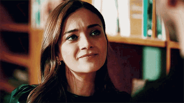 a woman with a sad look on her face is looking at a man in front of a bookshelf