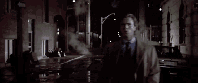 a man in a suit and tie is pointing a gun at the camera with a license plate that has the letters jc on it