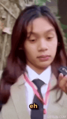 a woman in a suit and tie is holding a cell phone .
