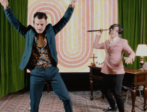 two men in suits are dancing in front of a colorful background