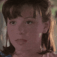 a close up of a girl 's face with a pink shirt on