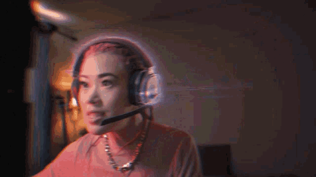 a woman wearing headphones and a necklace is sitting in front of a computer screen .