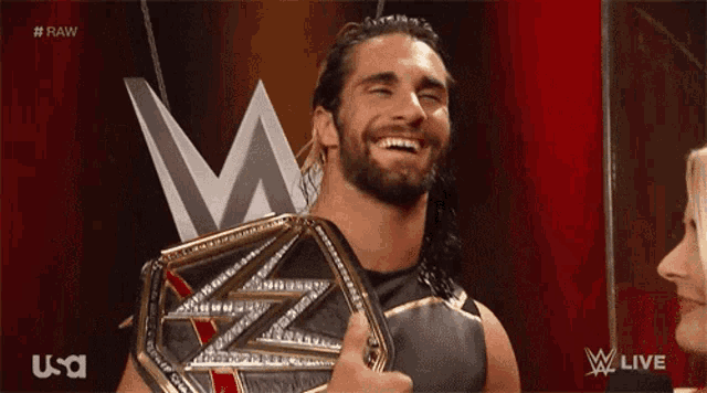 a man is holding a wrestling belt and giving a thumbs up sign