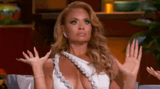 a woman in a very revealing white dress is sitting on a couch with her hands in the air .