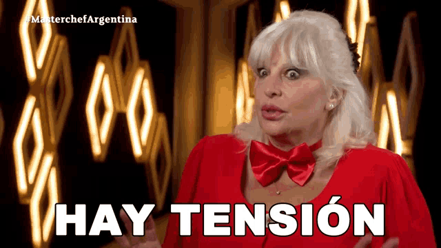 a woman wearing a red bow tie says hay tension in spanish