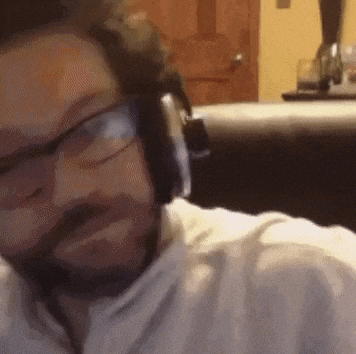 a man with a beard wearing headphones and glasses is laying on a couch