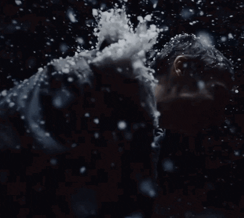 a man is being splashed with water in a dark room