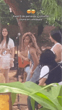 a group of women are standing in front of a microphone in a park .