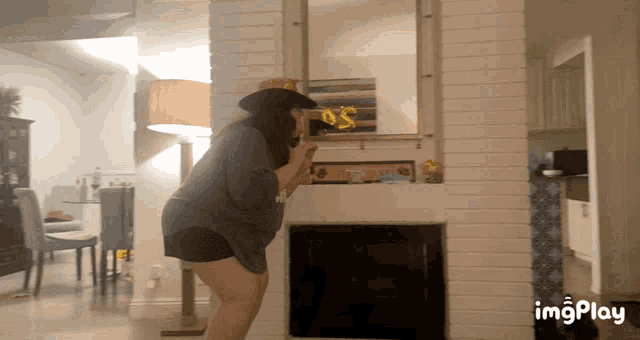 a woman in a hat is standing in front of a fireplace and a mirror with a balloon that says 5 on it