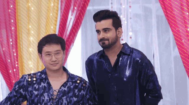 two men are standing next to each other and one is wearing glasses