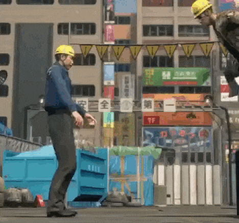 a man wearing a hard hat is standing in front of a building with a sign that says tf