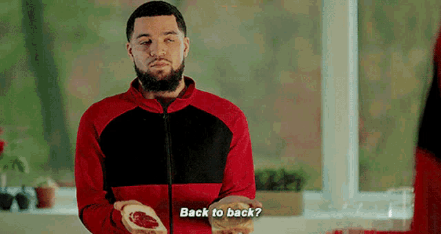 a man in a red and black jacket is holding a piece of meat and asking back to back ?