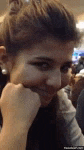 a woman is sitting at a table with her hand on her chin .
