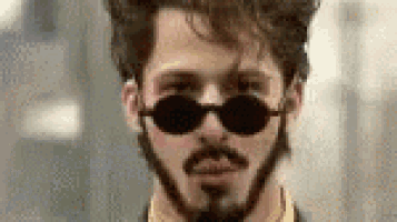a man with a beard and sunglasses is wearing a yellow shirt and a suit .