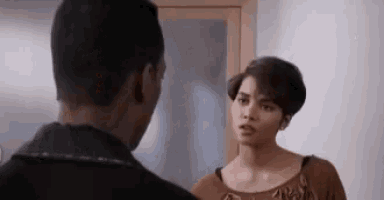 a man and a woman are standing next to each other in a room and looking at each other .