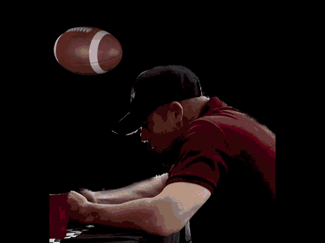 a man in a baseball cap sits at a table with a diagram behind him that says ' seam ' on it