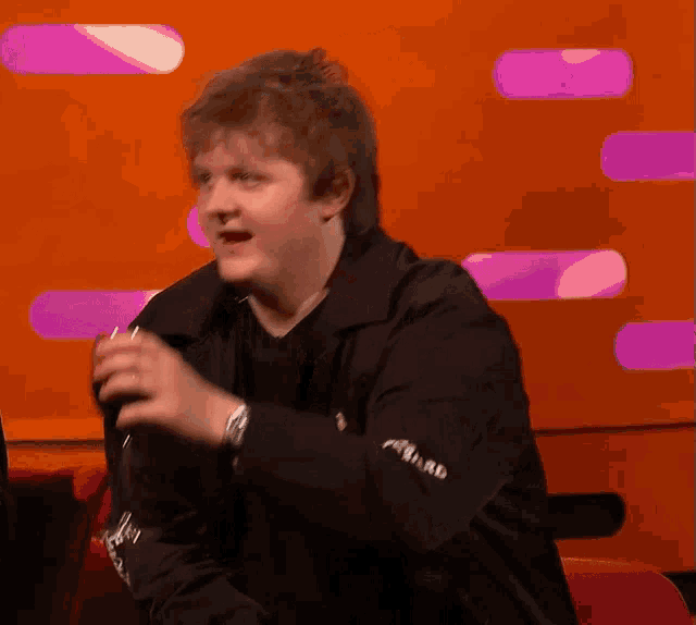 a man wearing a black jacket with the word reward on it