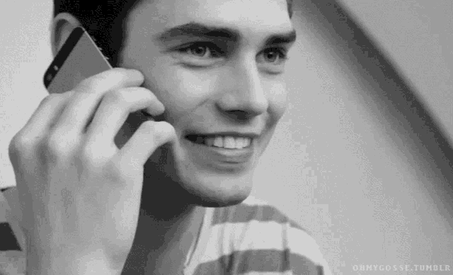 a man is smiling while talking on his cell phone